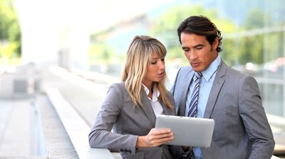 Optimized-stock-footage-business-team-using-electronic-tablet-outside-offices-building